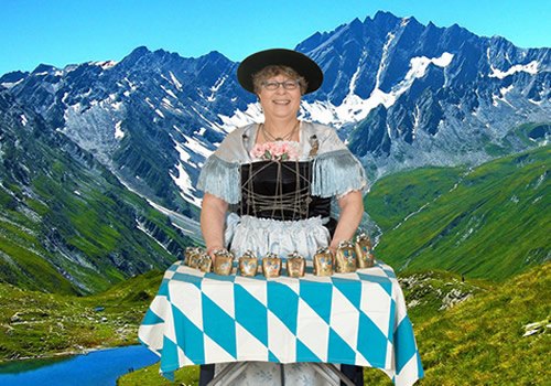 Cowbell player in a dirndl with a row of tuned bells on a blue and white table