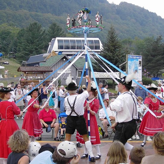 Dancers in Tracht weaving ribbons around a maypole